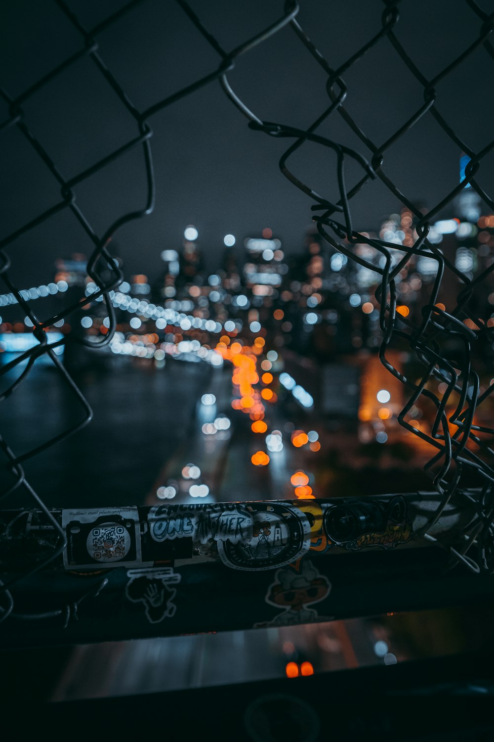 a view of a city at night through a chain link fence