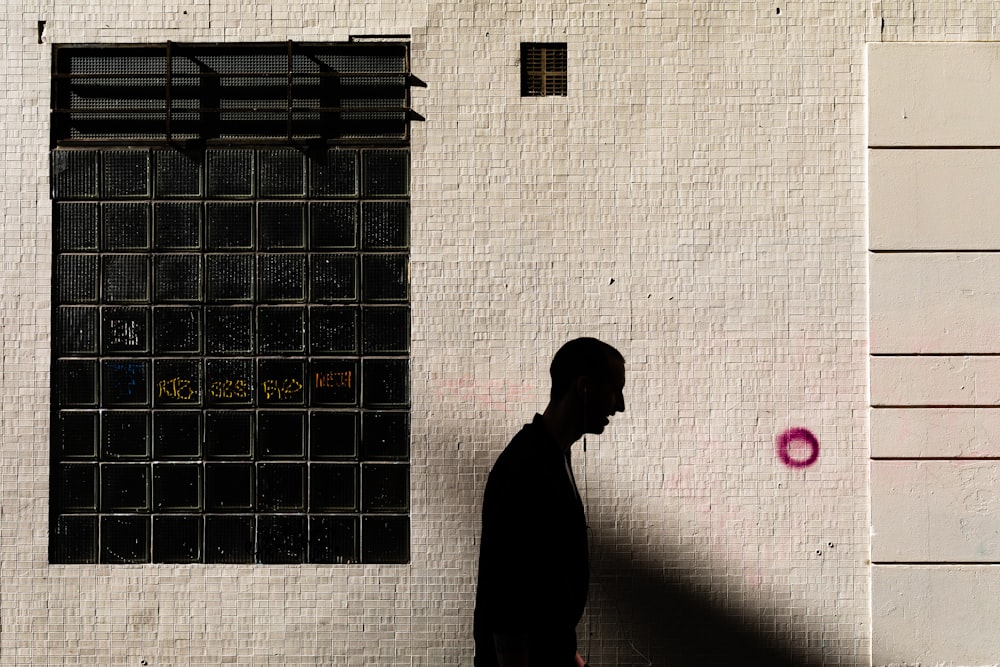 a man walking down a street past a white building