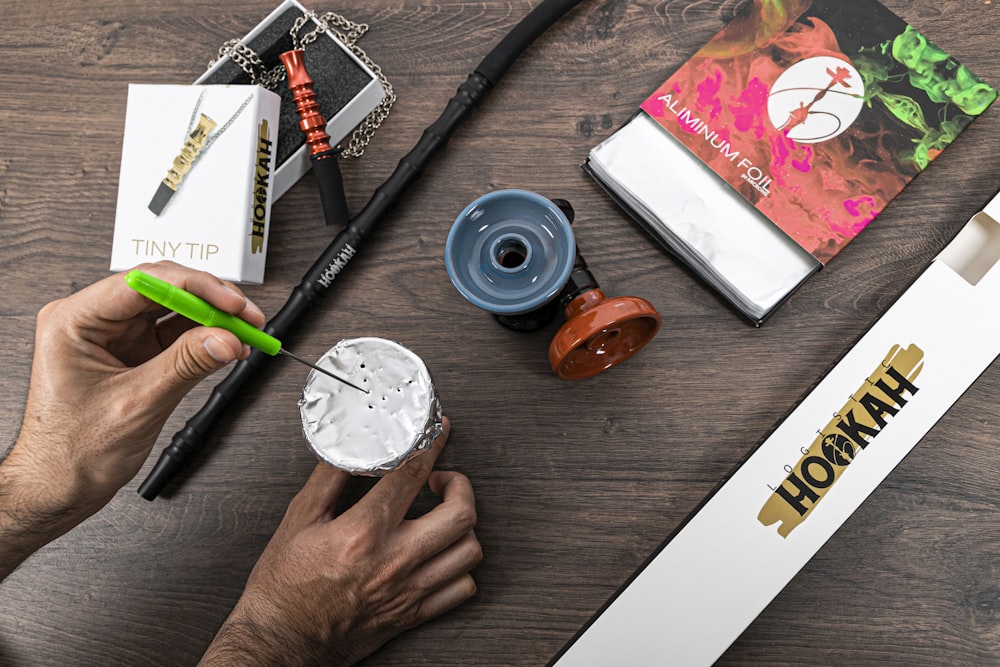 a person holding a paintbrush next to some items on a table