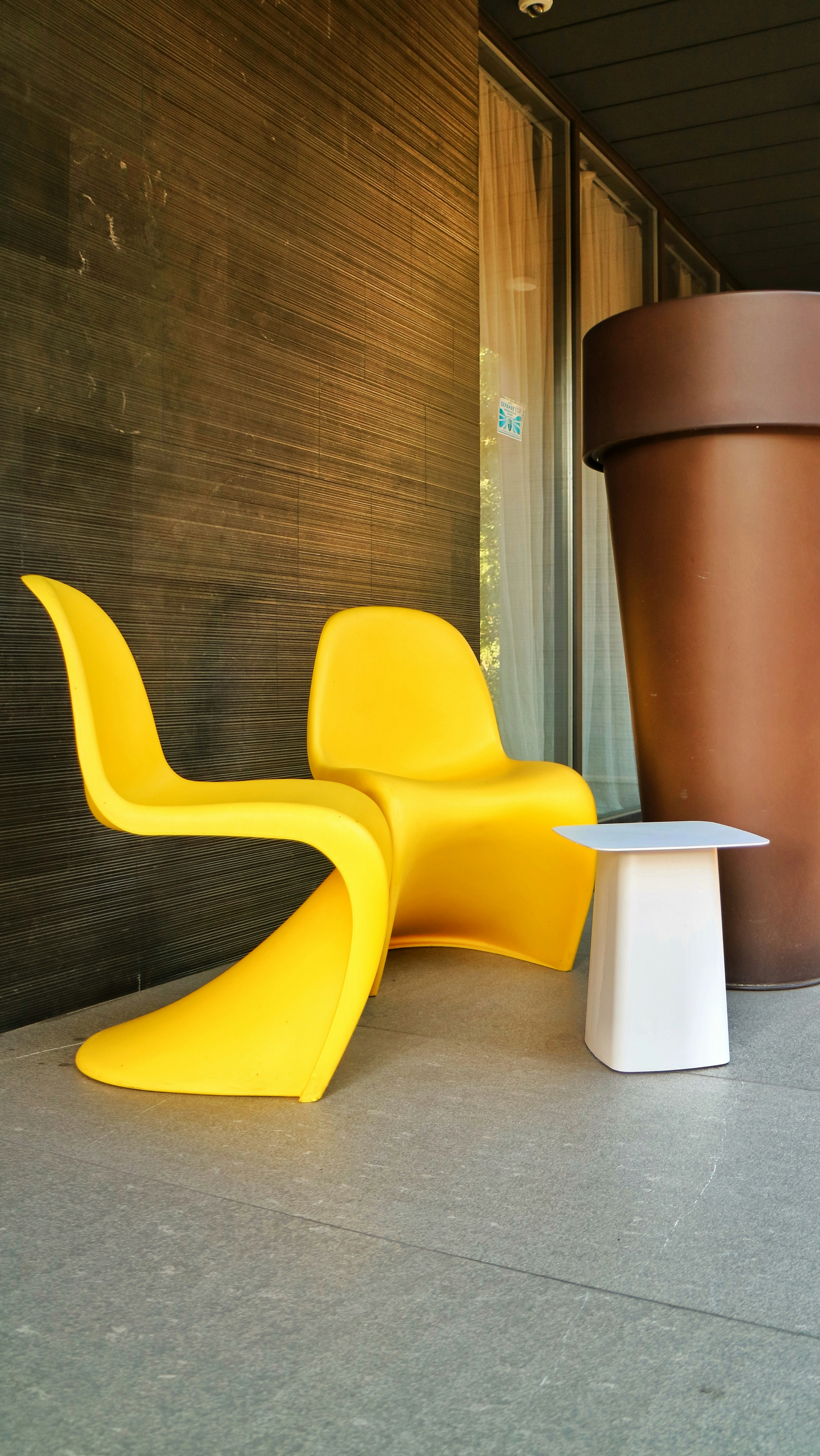 a yellow chair sitting next to a brown pot