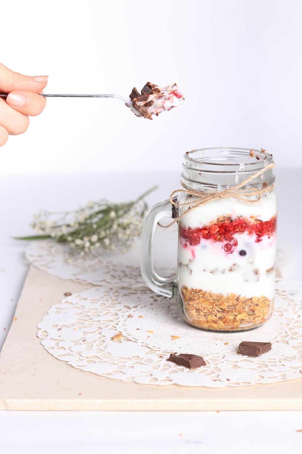 a person holding a spoon over a jar of food