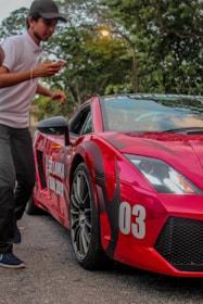 A person in a white shirt and cap appears to be moving past a red sports car with the number 03 on its front. The car has visible rain droplets and is set against a backdrop of trees. The words 'Sri Lanka Run 2019' are also visible on the side of the car.