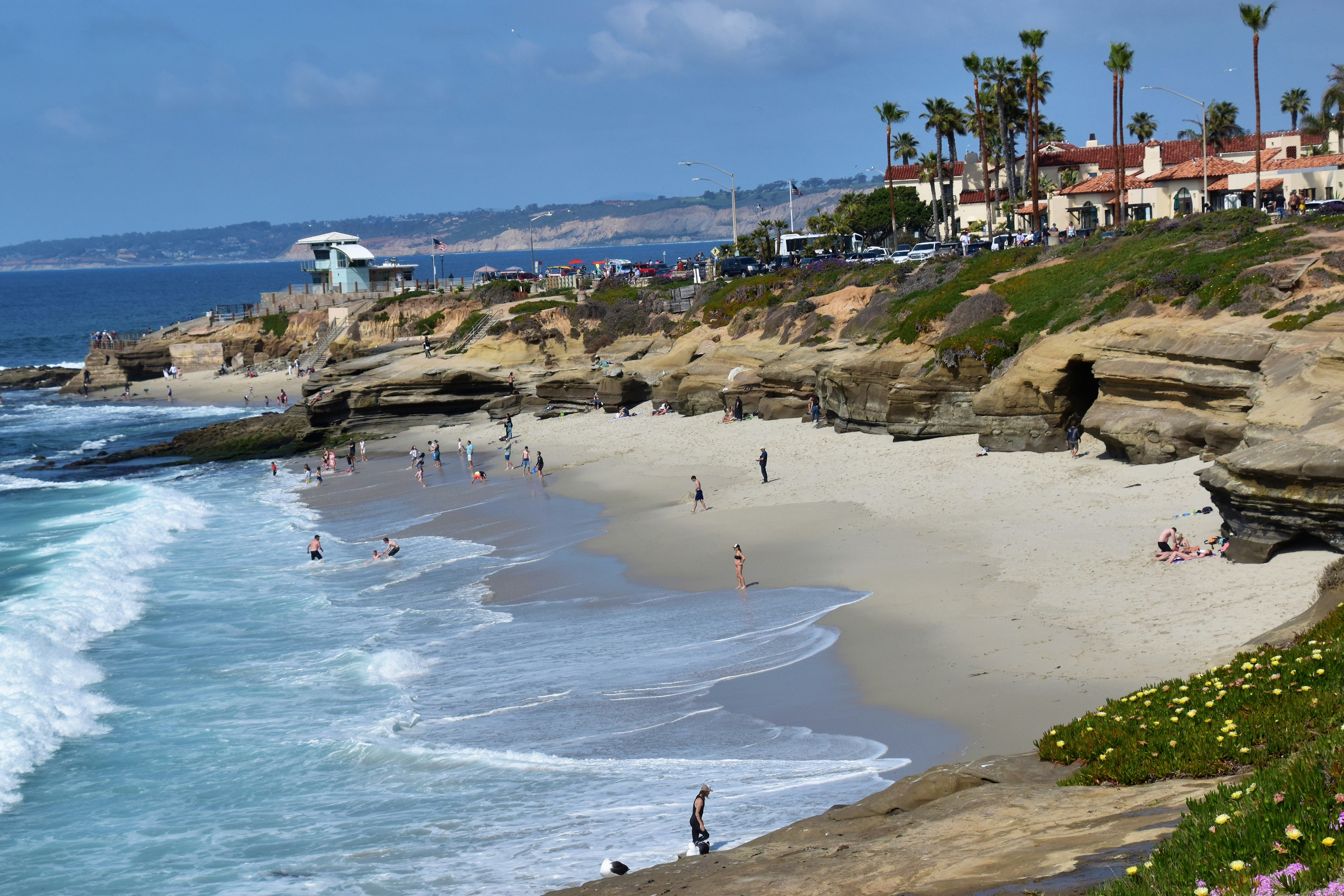 a beach with people walking on it next to the ocean