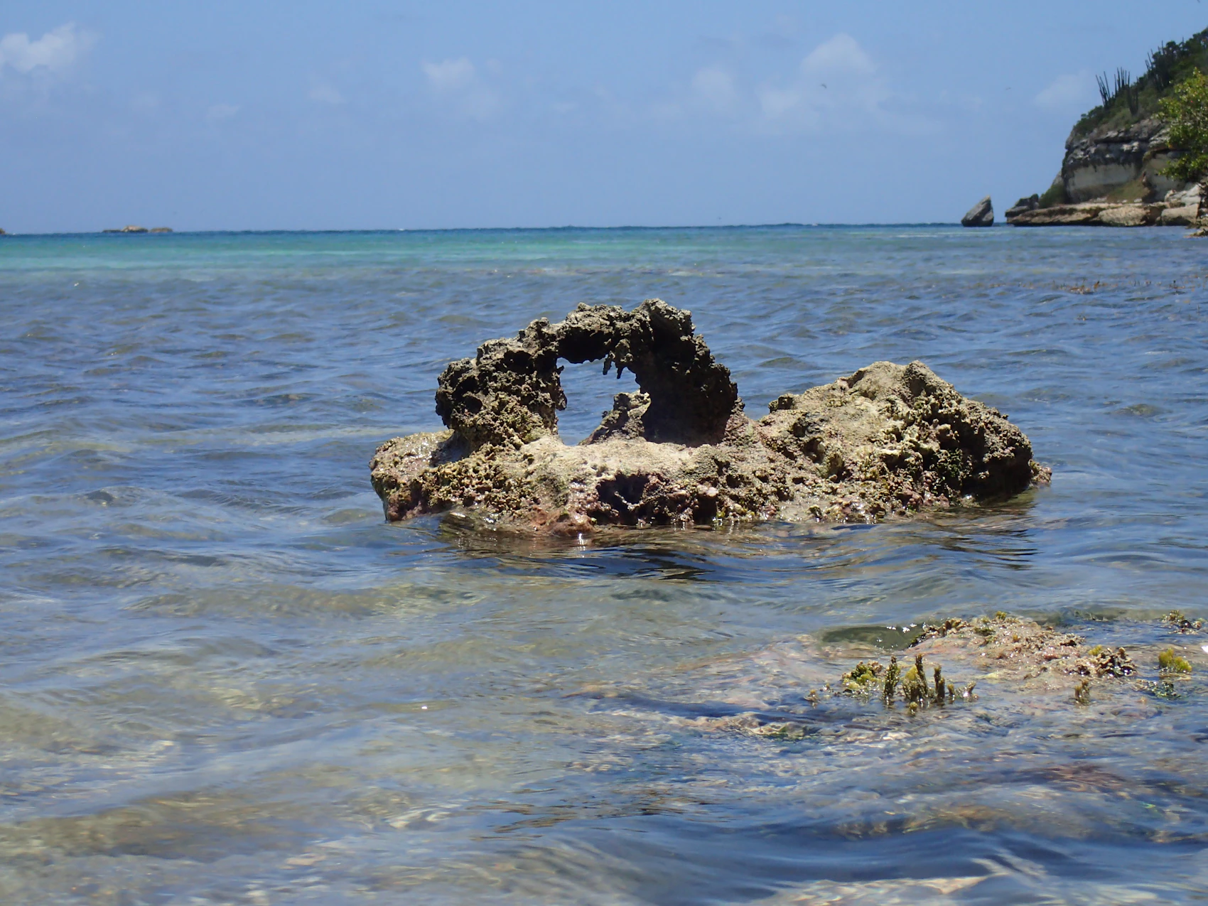 A small natural rock arch in the shallow sea at Great Bird Island, Antigua