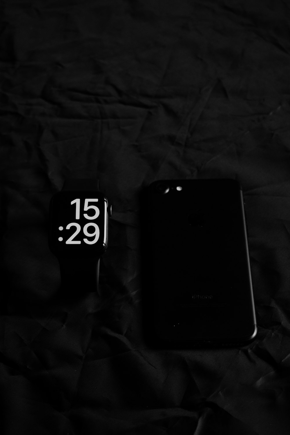 a cell phone sitting on top of a bed next to a clock