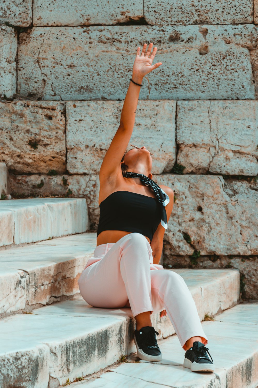 a woman sitting on steps reaching up in the air