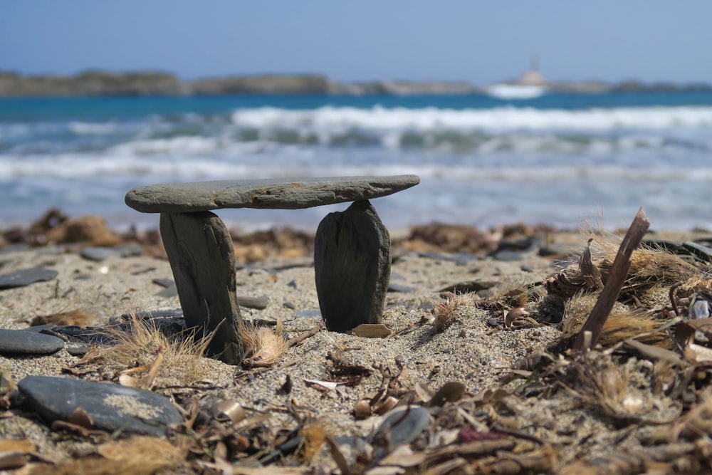 a stone bench sitting on top of a sandy beach
