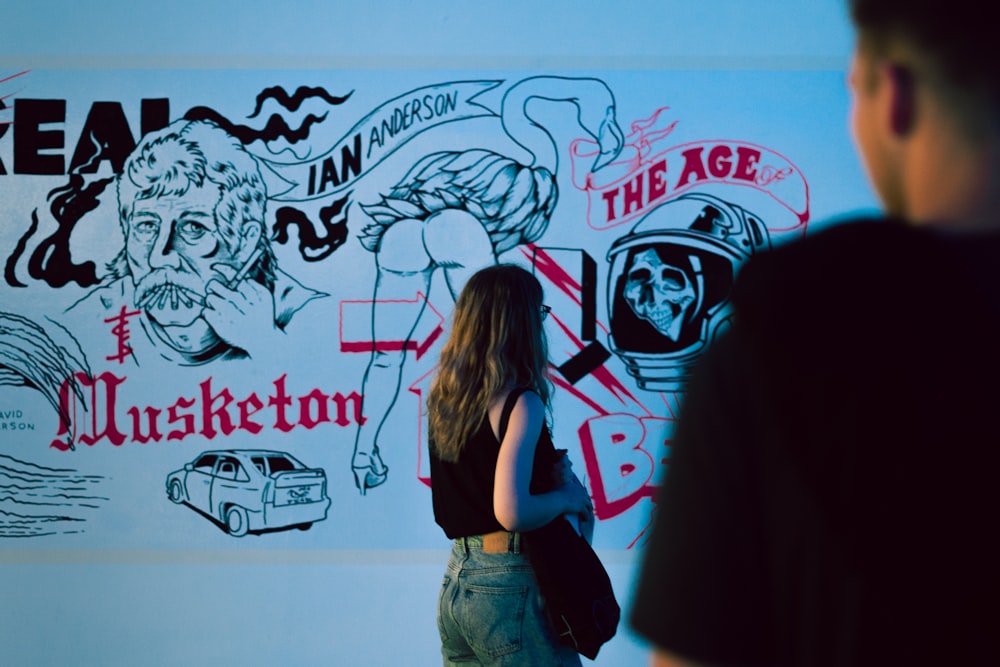 a woman standing in front of a wall with a drawing on it