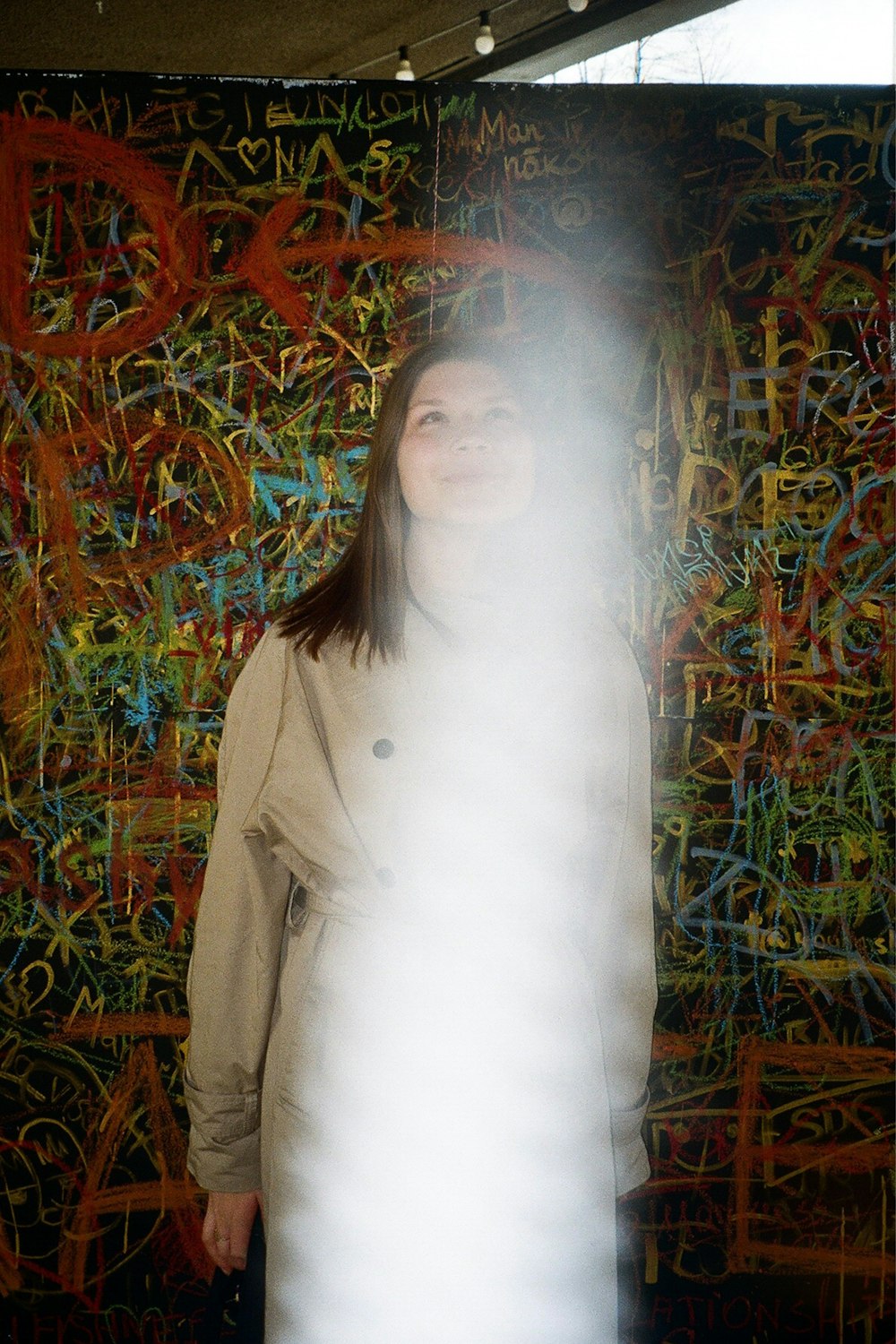 a woman standing in front of a wall covered in graffiti