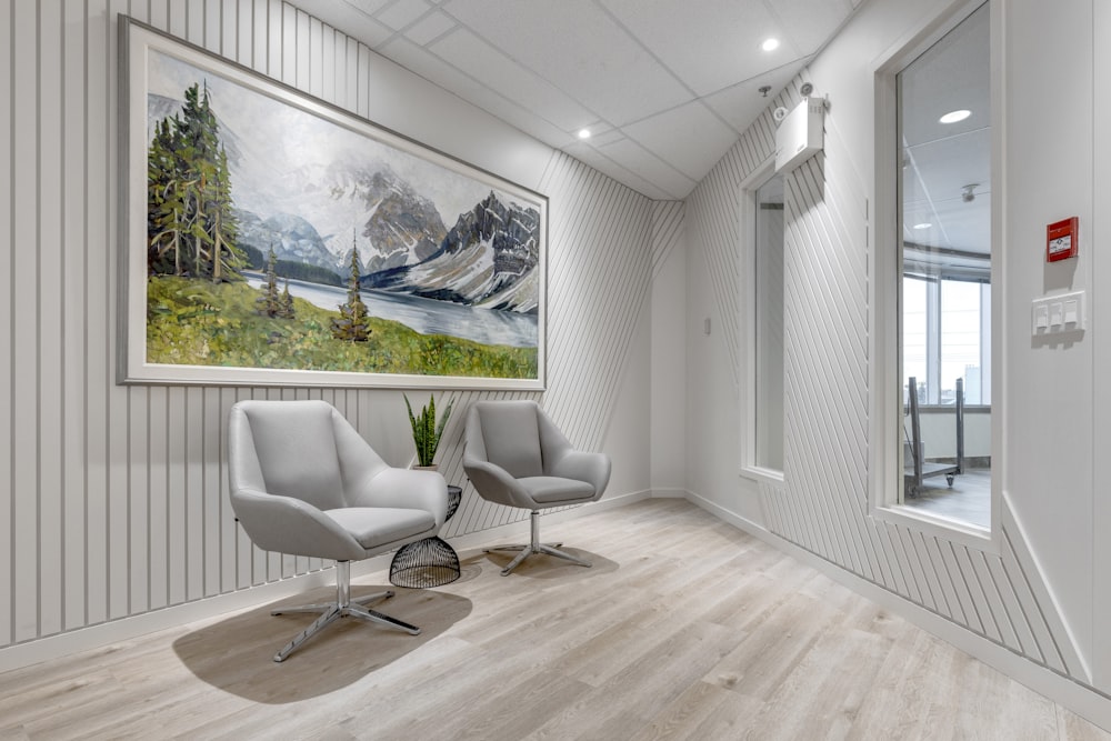 a white room with two chairs and a painting on the wall