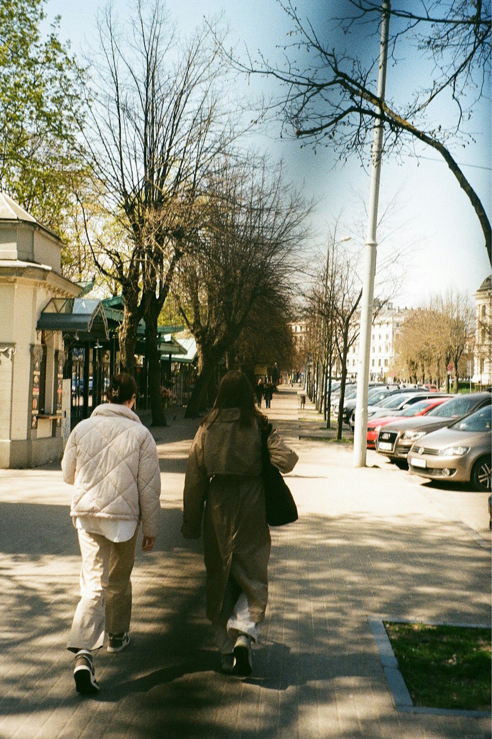 a couple of people walking down a sidewalk