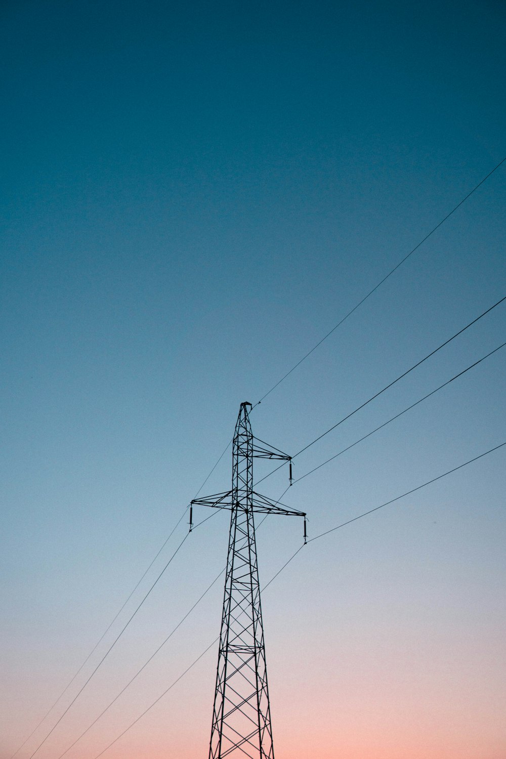 a high voltage power line with a pink sky in the background