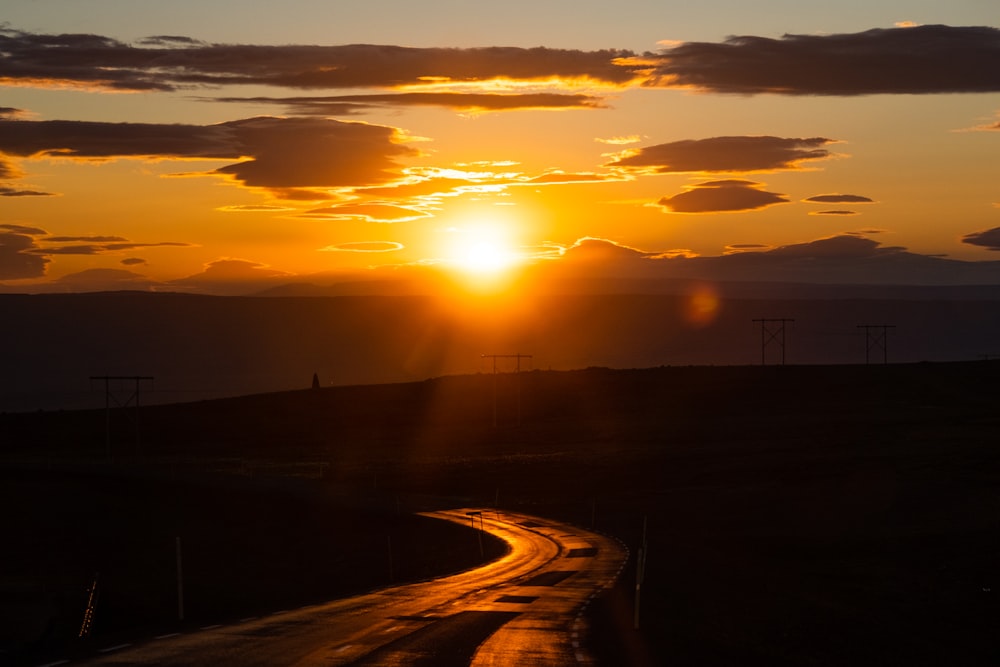 the sun is setting over a rural road