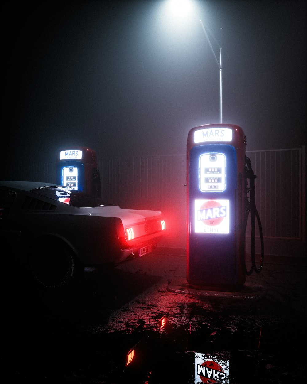 a gas station at night with two cars parked