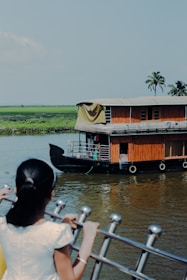 a woman standing on a boat looking at a houseboat