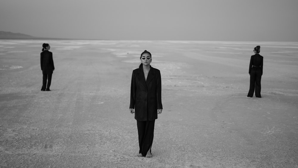 a woman in a suit standing in the middle of a desert