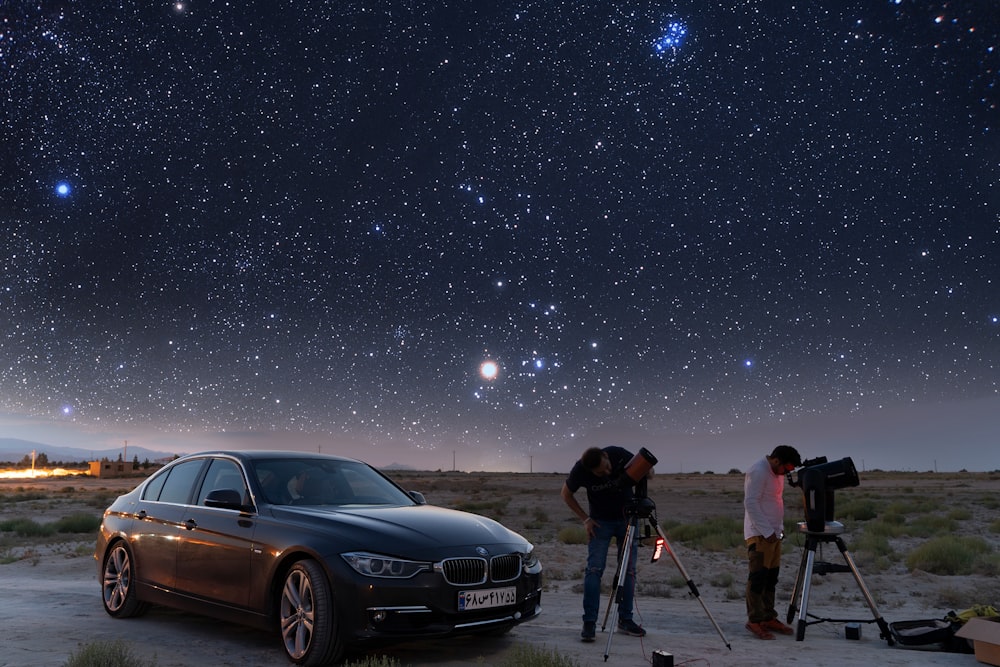 a couple of people standing next to a car