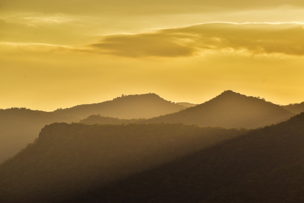 the sun is setting over the mountains in the distance