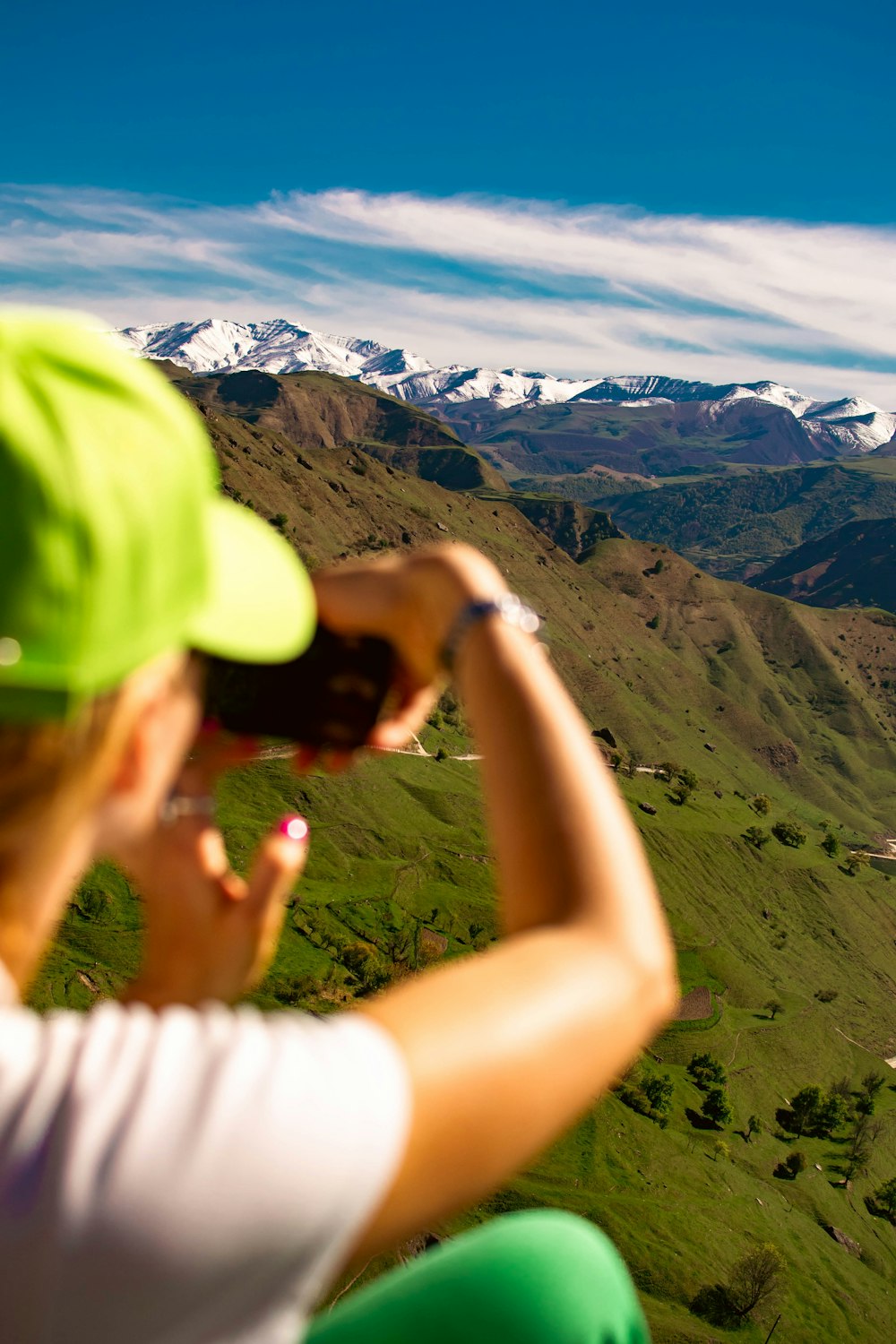 a woman taking a picture of a valley with mountains in the background