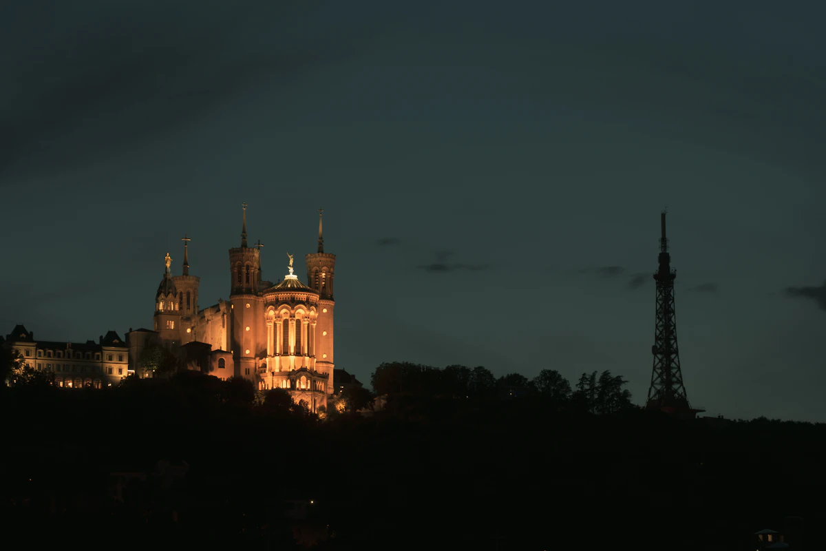 The Fourvière basilica and its metal tower lit up at night above Lyon