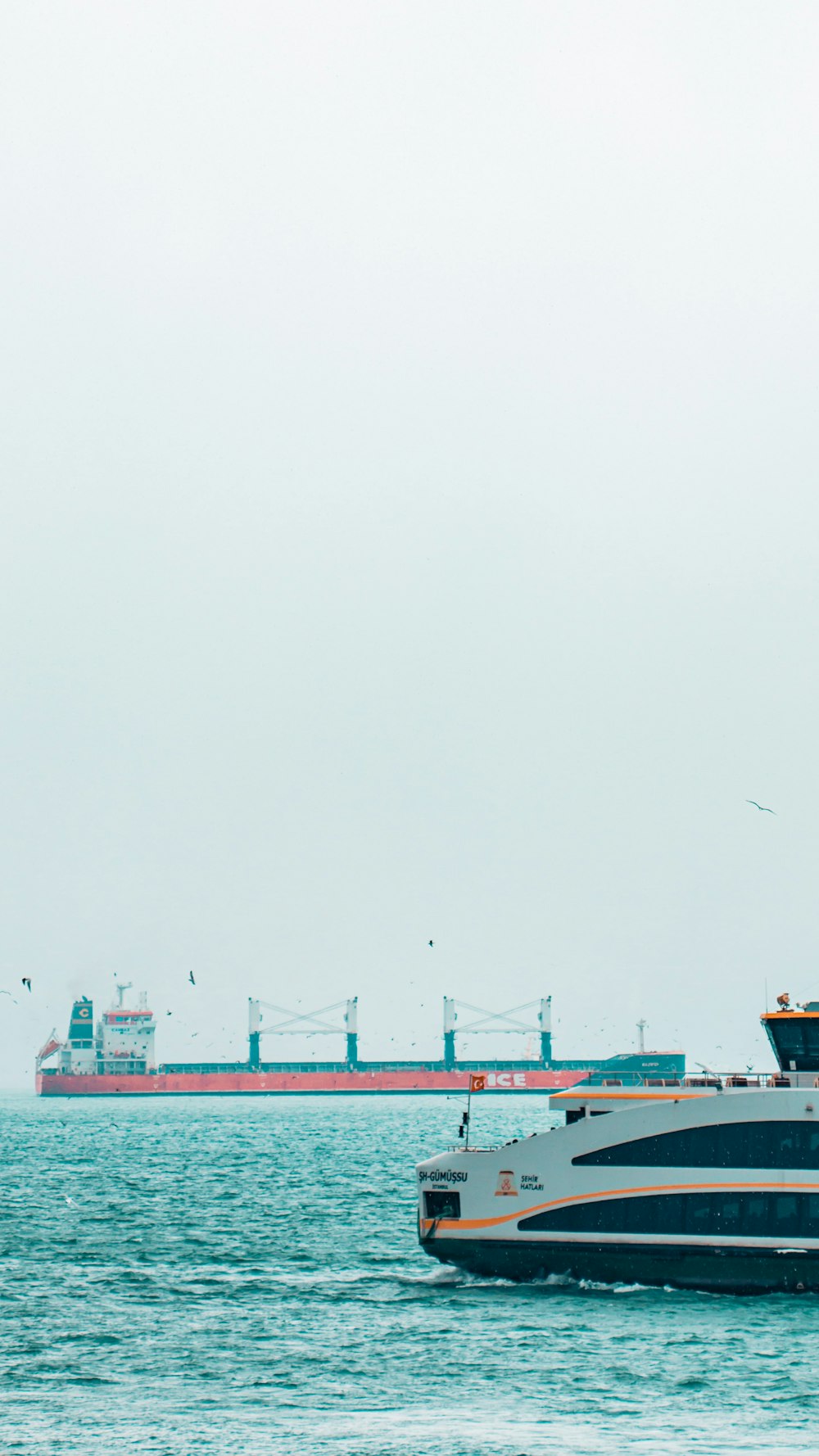 um barco na água com um grande navio de carga no fundo