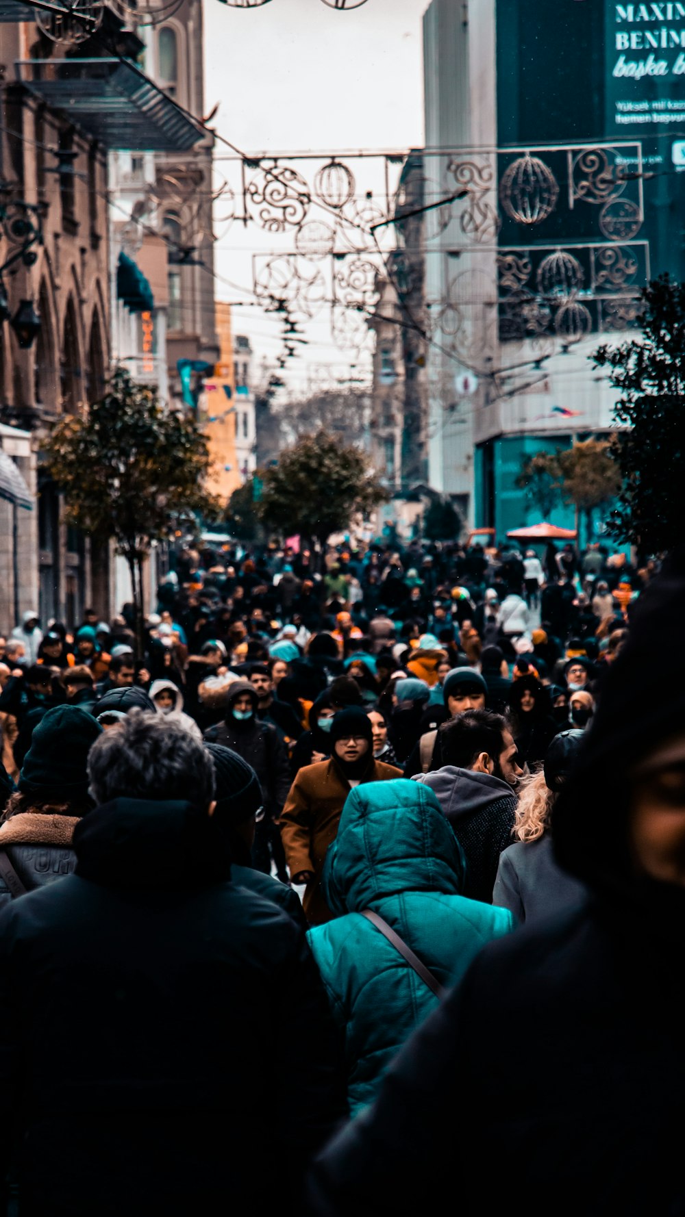 a crowd of people walking down a street next to tall buildings