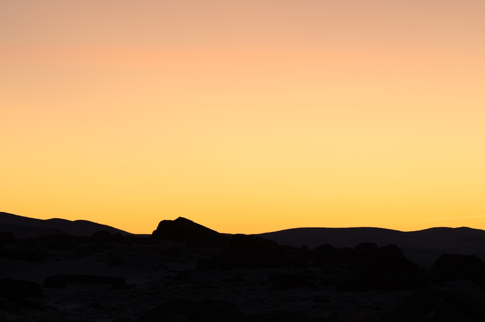 a silhouette of a person standing on top of a hill