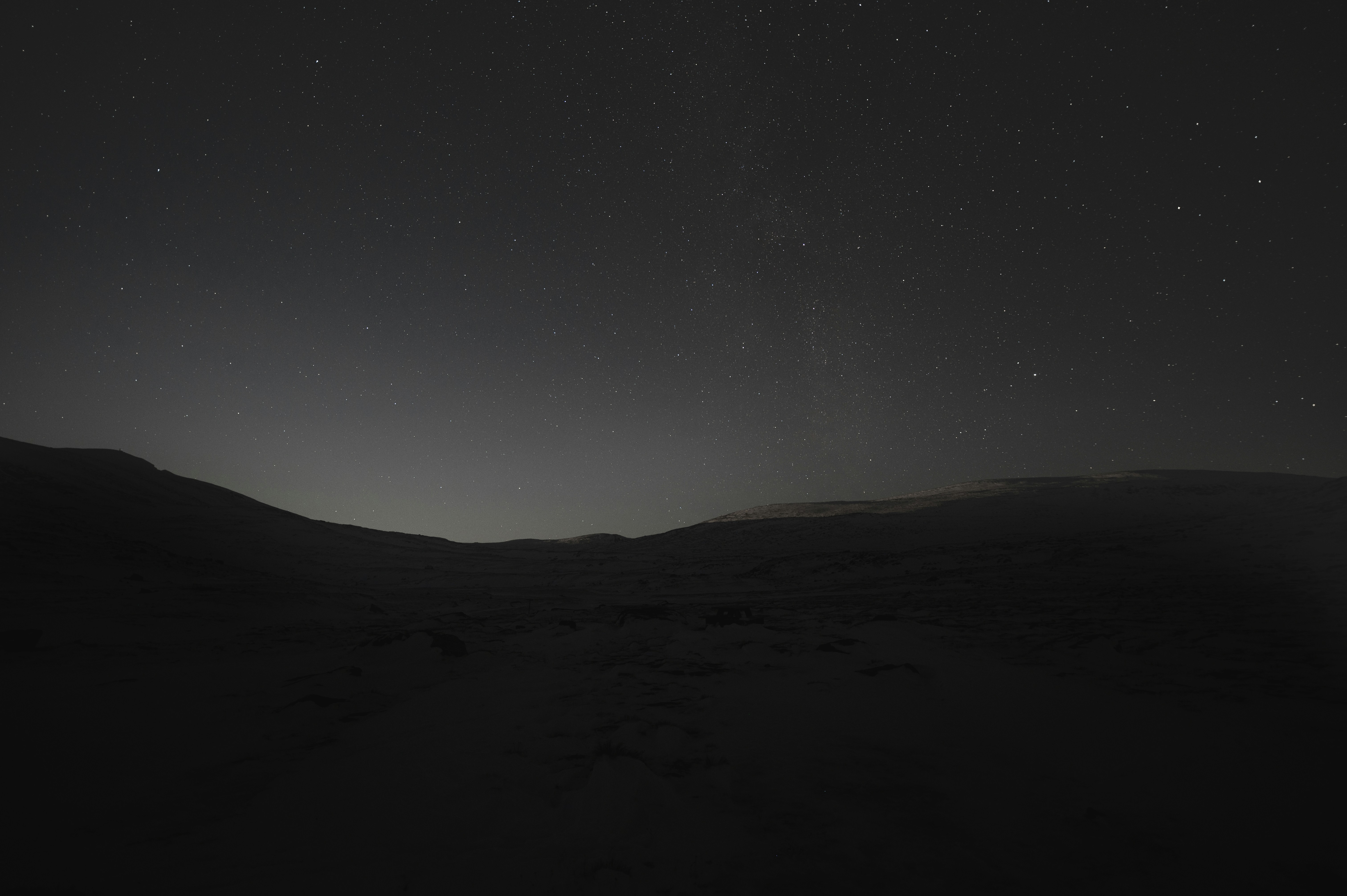 the night sky with stars above a hill