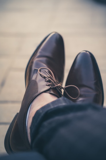 a person's feet wearing a pair of brown shoes