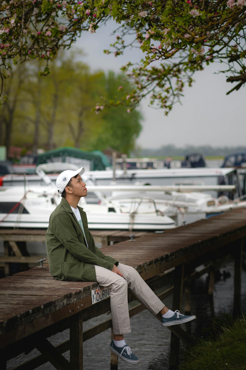 a man sitting on a wooden dock next to boats