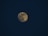 A full moon is prominently centered against a deep, dark blue night sky. The moon's surface details are visible, showing its craters and lunar patterns.