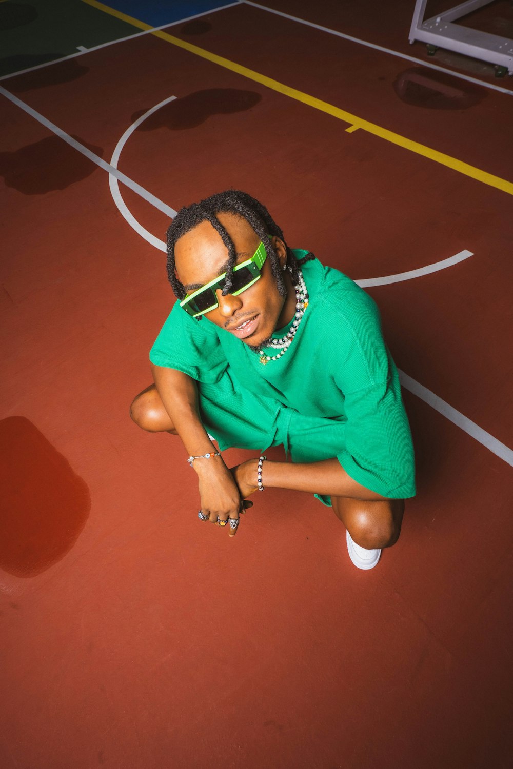 a woman sitting on a basketball court wearing sunglasses