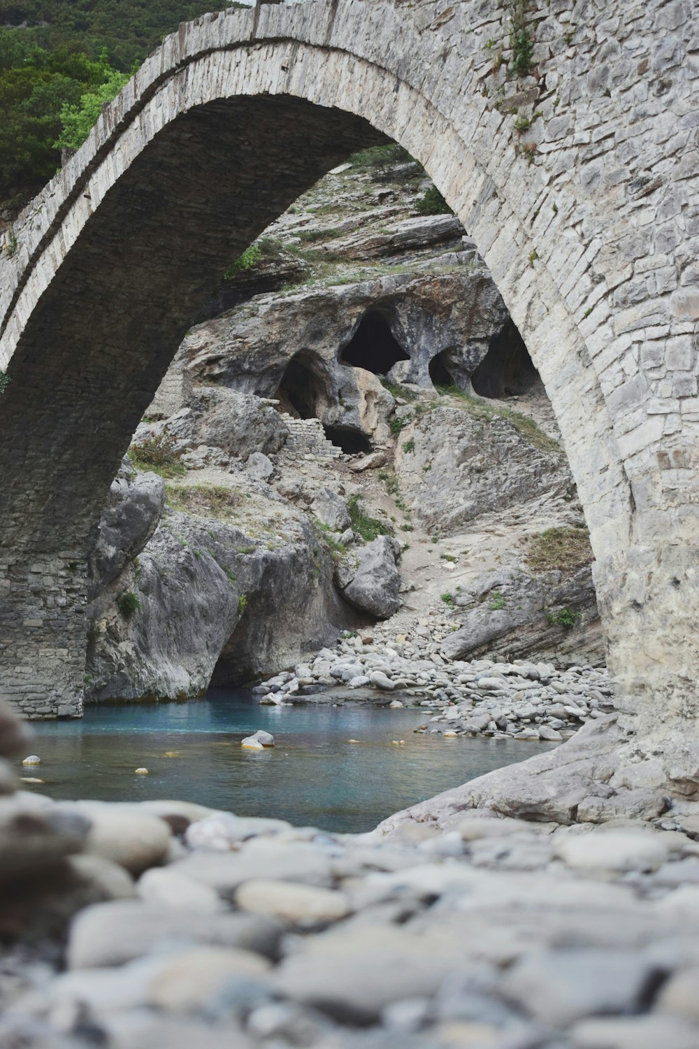 a stone bridge over a river surrounded by rocks