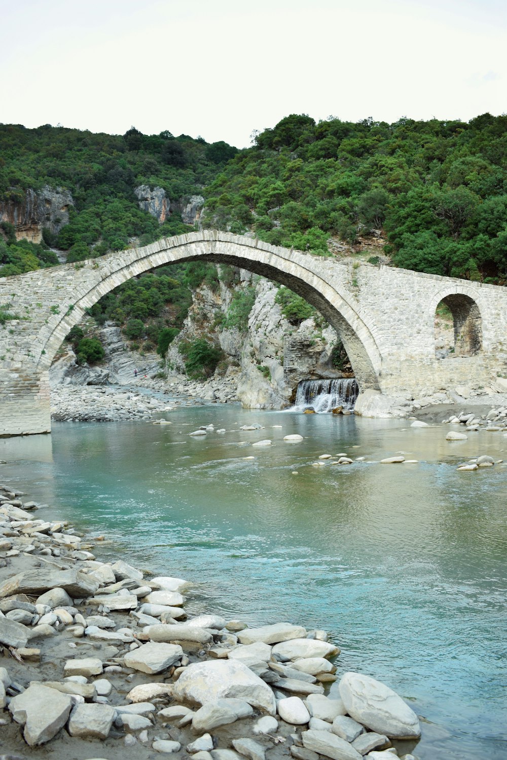 a stone bridge over a river with a waterfall