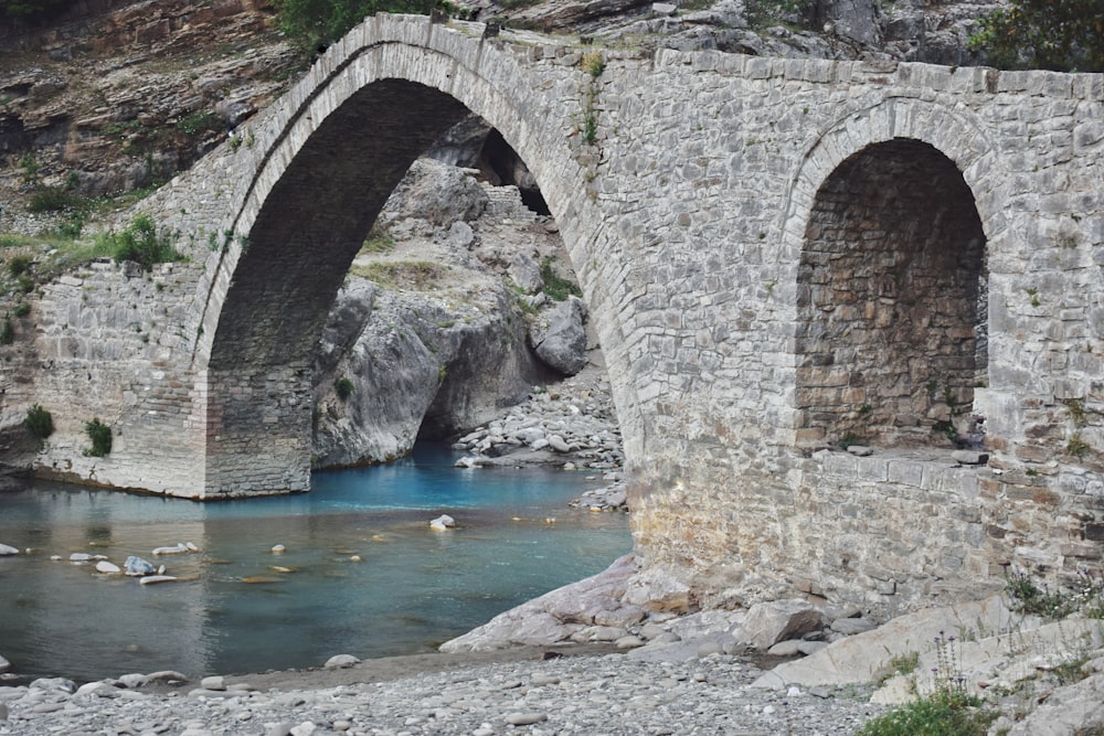 a stone bridge over a river surrounded by rocks