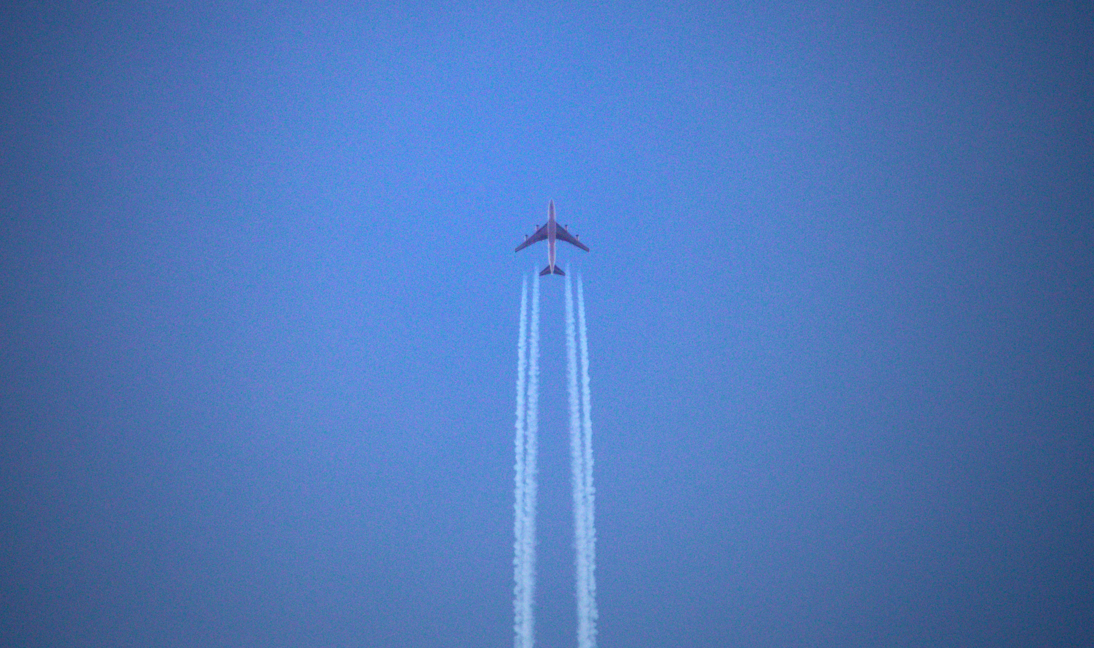 a jet flying through a blue sky leaving a trail of smoke behind it, 