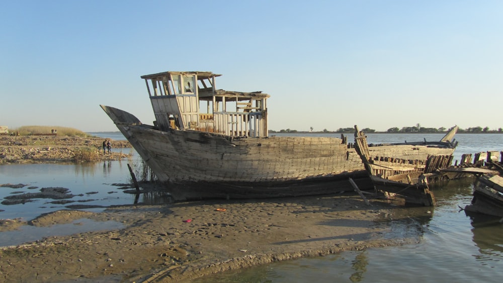 a boat sitting on top of a beach next to a body of water