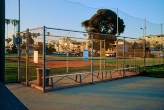 a baseball field behind a fence with a baseball field in the background