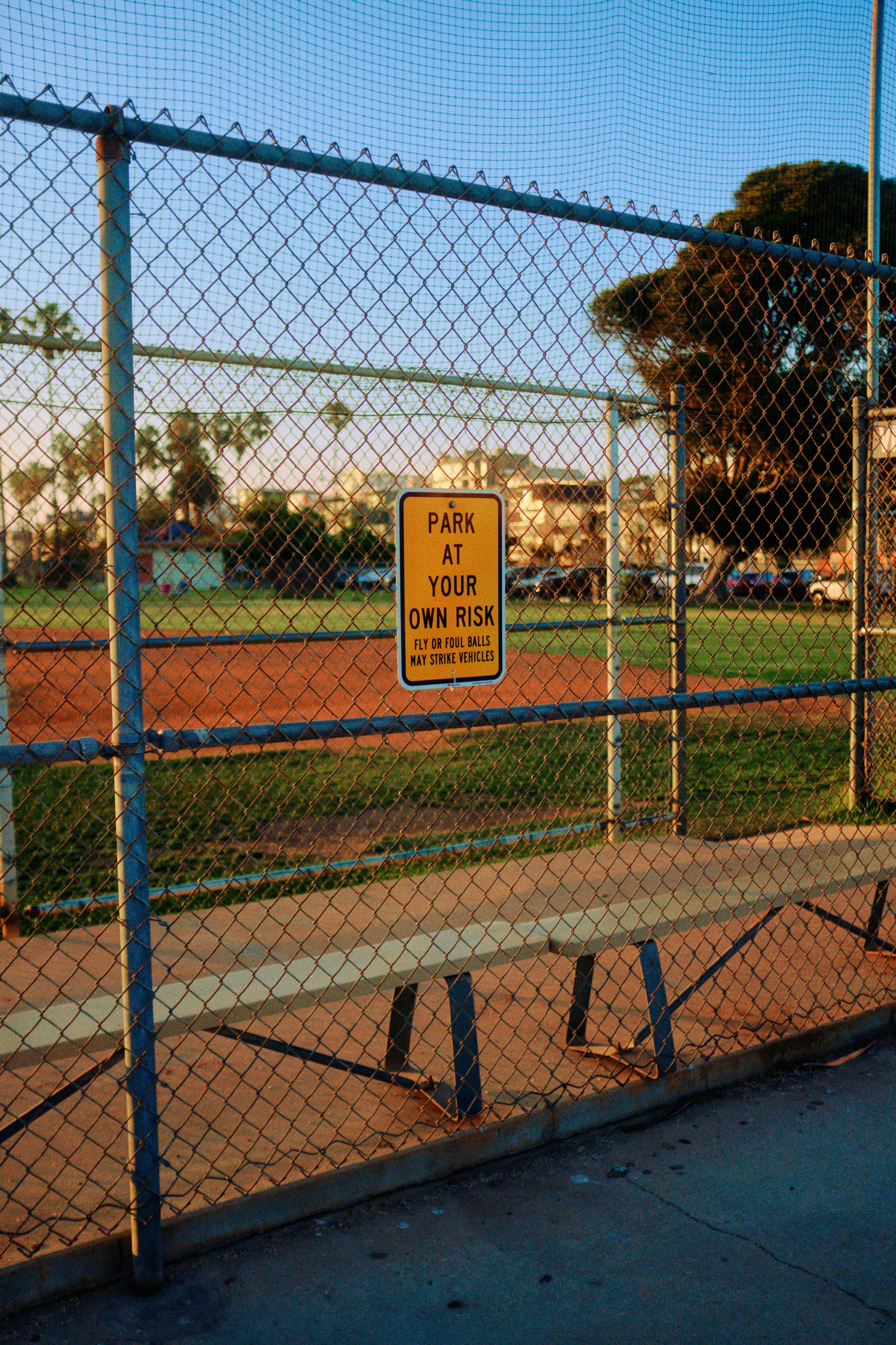 Caution sign on the fence of an empty public baseball pitch / field near Redondo Beach in Los Angeles, California.