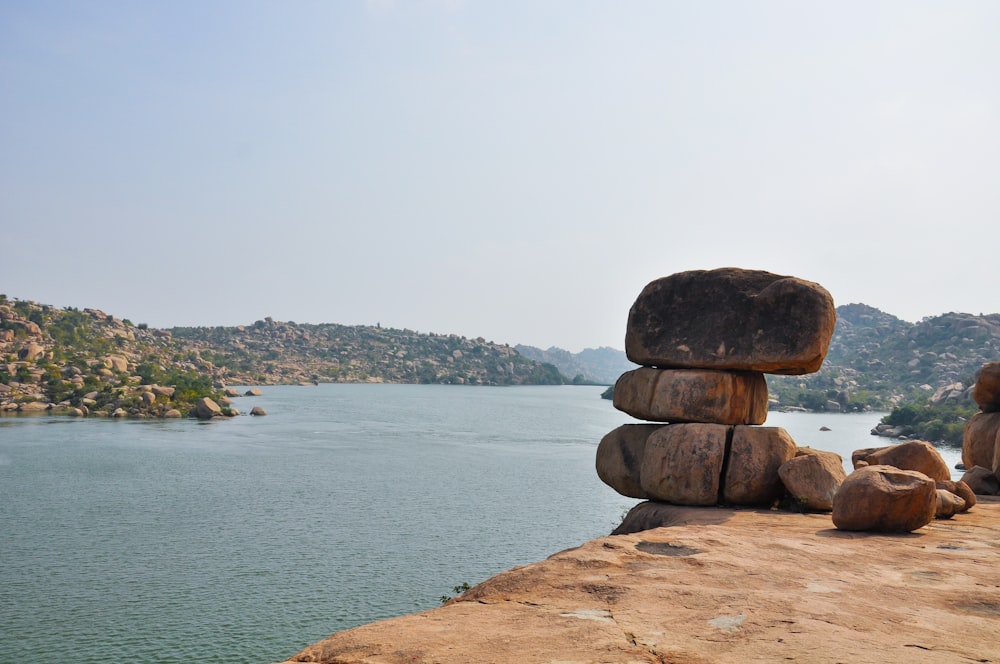 a stack of rocks sitting on top of a cliff next to a body of water