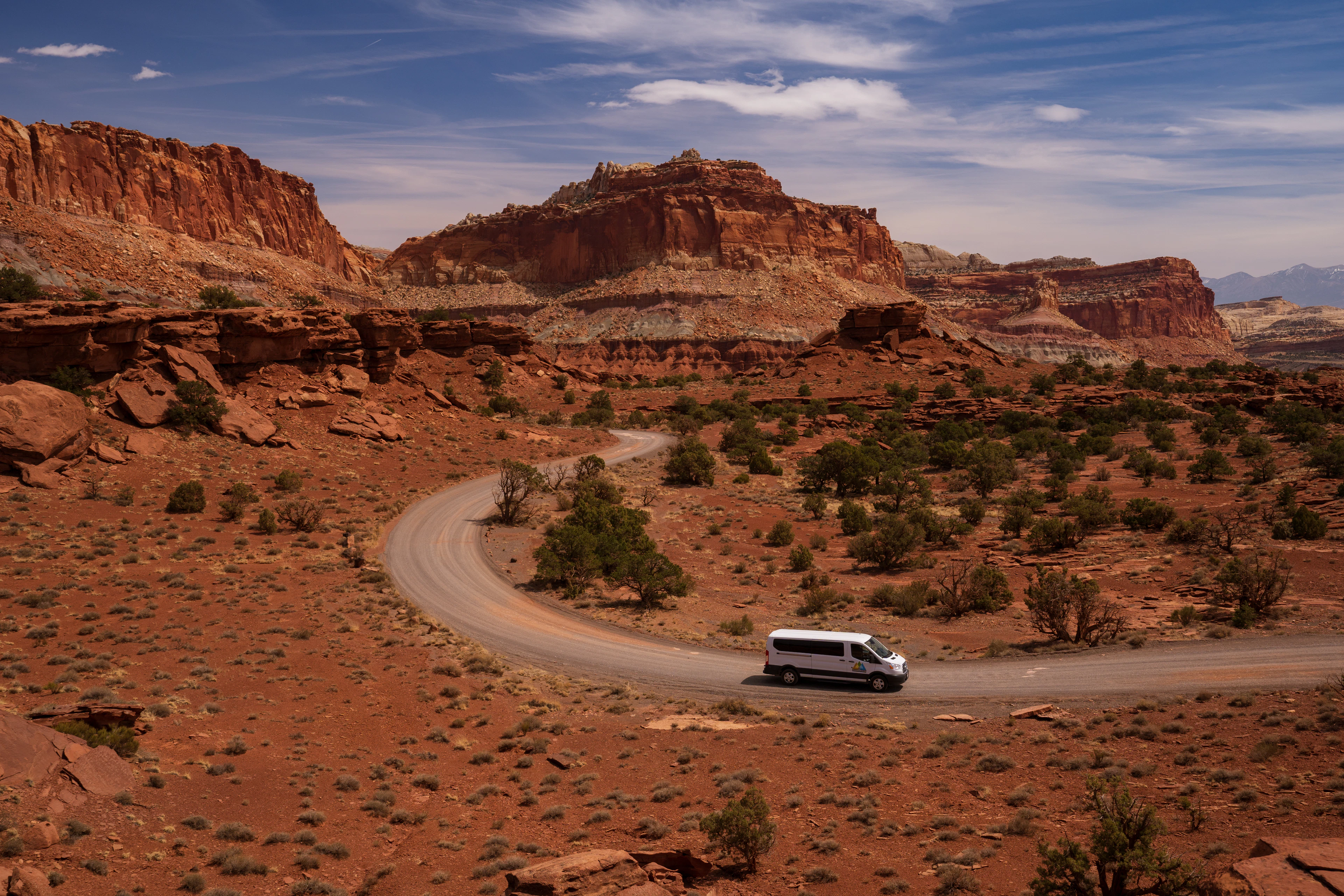 A van on a winding road through red-rock country in southern Utah