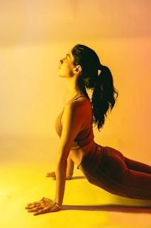 a woman in a red top is doing a yoga pose