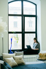 a woman sitting on a couch using a laptop computer