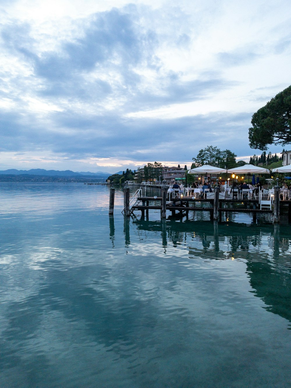 a dock with tables and umbrellas on the water