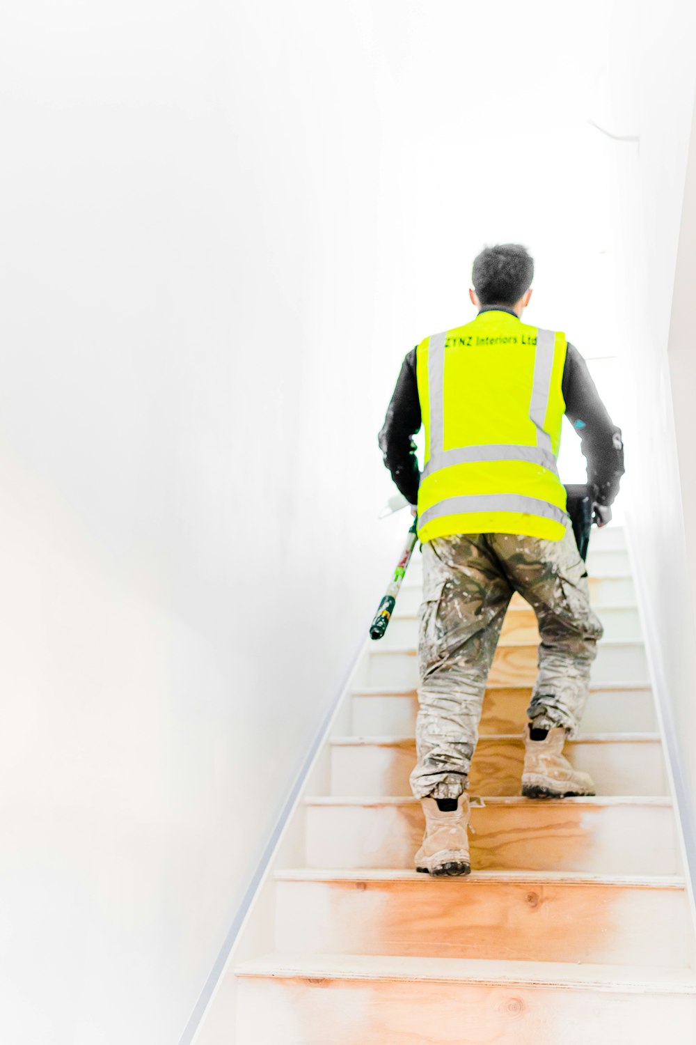 a man in a safety vest climbing up a flight of stairs