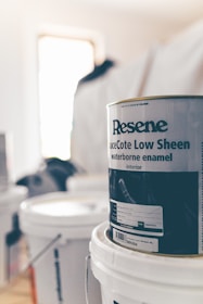 a can of paint sitting on top of a white bucket
