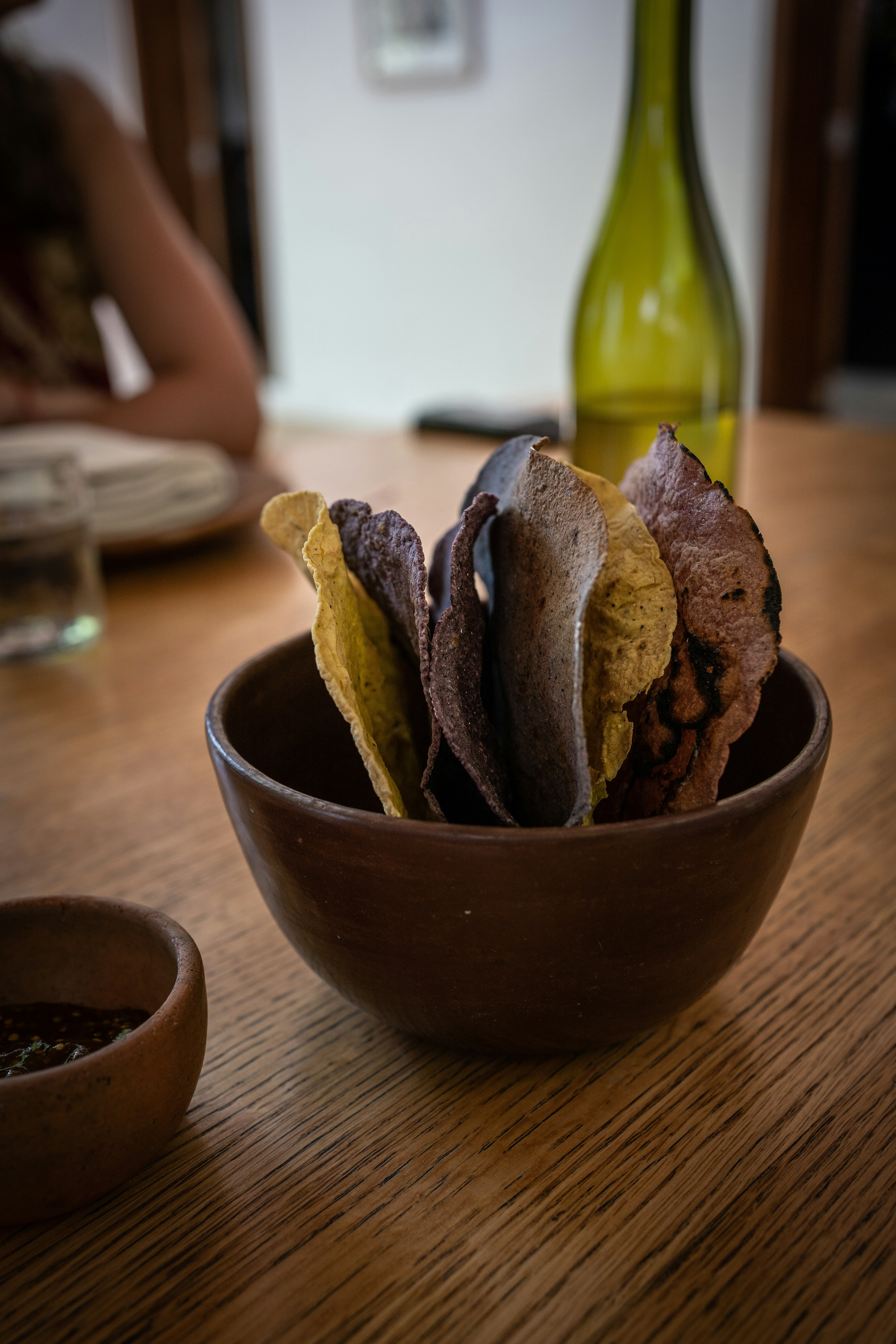 a wooden bowl filled with chips on top of a wooden table