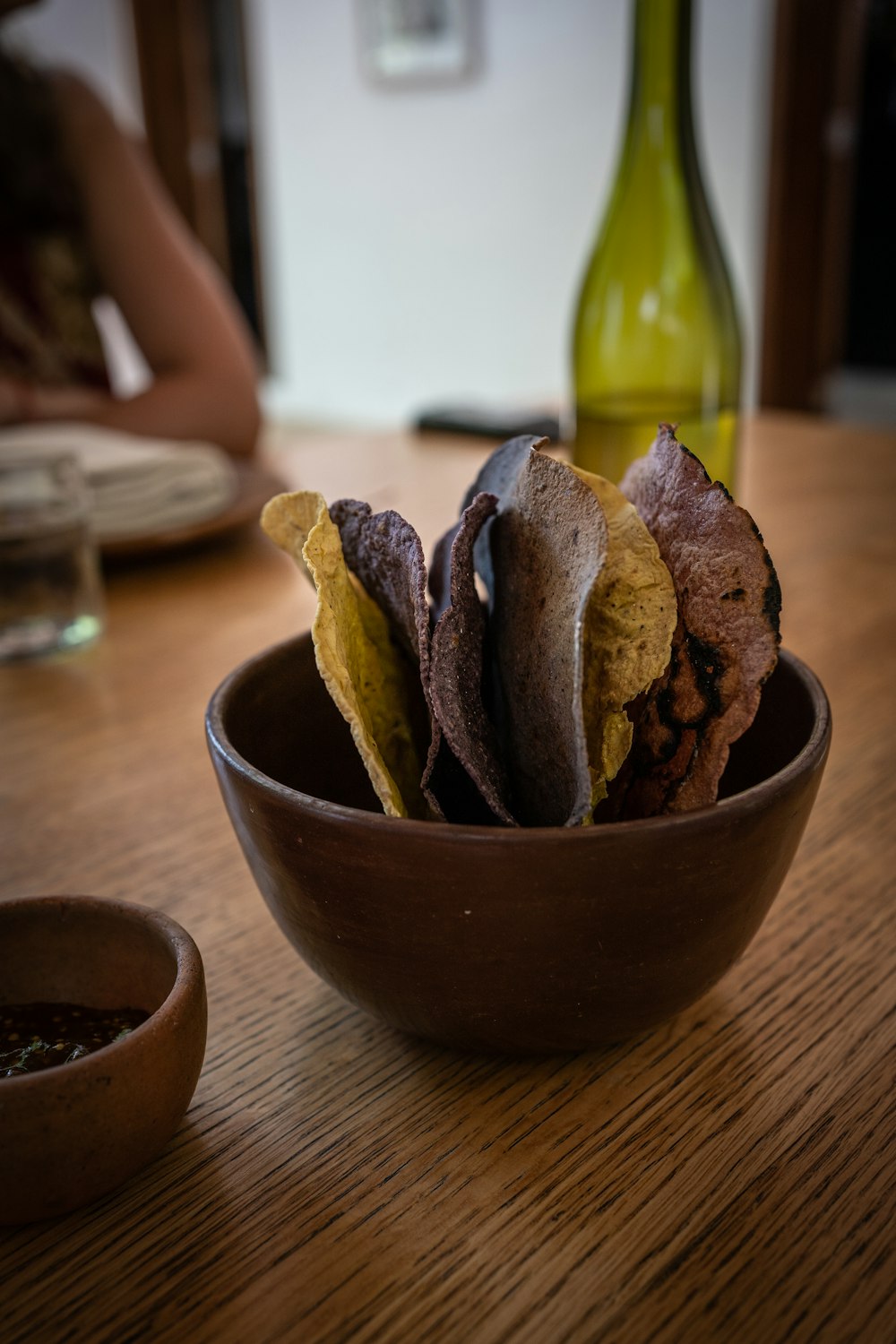 a wooden bowl filled with chips on top of a wooden table