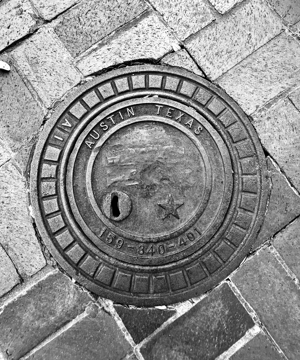 a manhole cover on a brick sidewalk