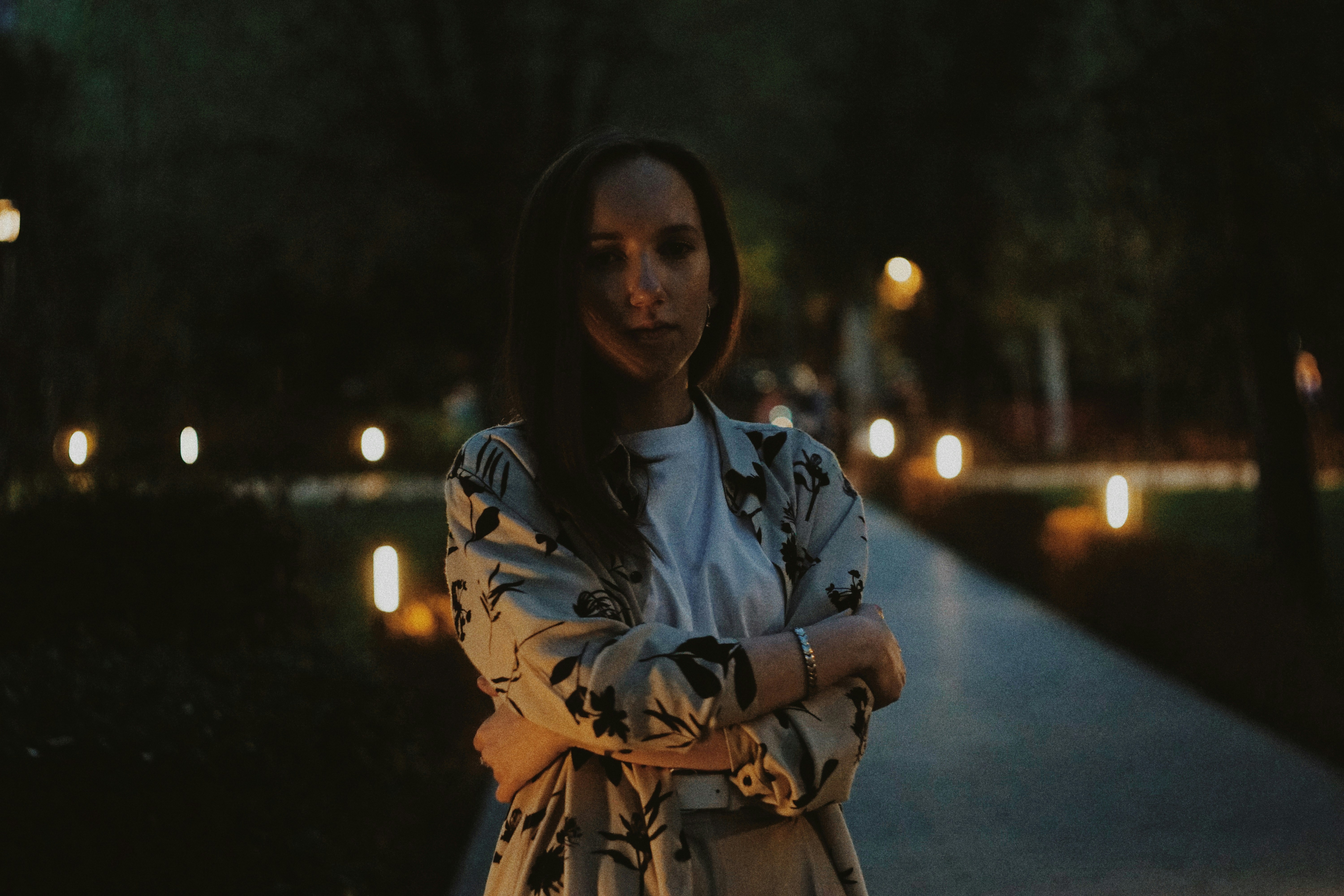 a woman standing on a sidewalk with her arms crossed